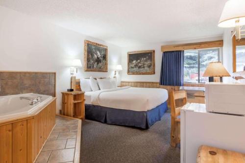 a hotel room with a bed and a bath tub at Sandpoint Inn in Ponderay