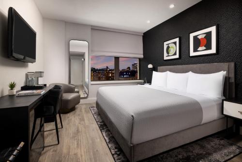 a bedroom with a bed and a desk and a television at Arthouse Hotel in New York