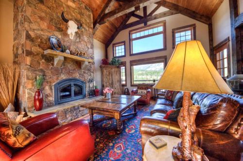a living room with leather furniture and a stone fireplace at Antler Ridge Lodge in Big Sky