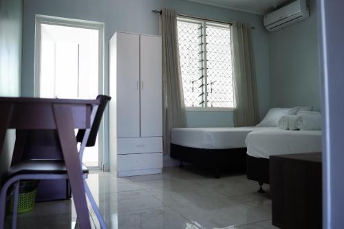 een slaapkamer met een bed, een kast en 2 ramen bij Hotel Laimoa in Apia