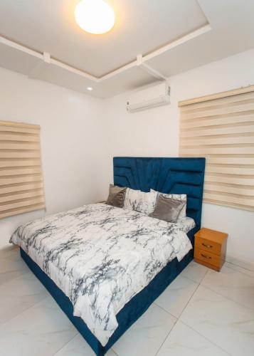 a bed in a white room with a blue headboard at Tranquil 5BR Duplex in Lekki in Maiyegun
