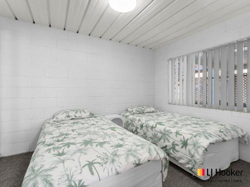 two beds in a room with white walls at Bay Breeze in Iluka