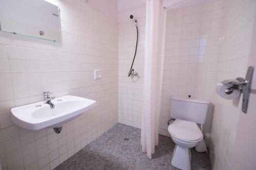 Baño blanco con aseo y lavamanos en Résidence les Arbousiers, en Saint-Florent