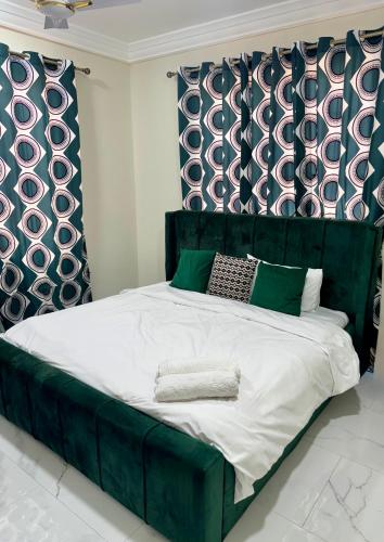 a bed with a green headboard in a bedroom at Modern 1 Bedroom Ground Floor Apartment with Serene Mountain Views, close to Aburi Walking Trail in Oyarifa