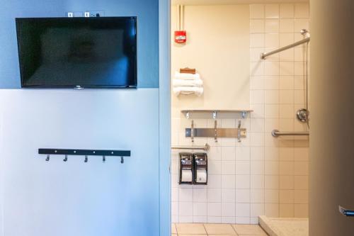 a bathroom with a tv on the wall and a shower at HI Chicago Hostel in Chicago