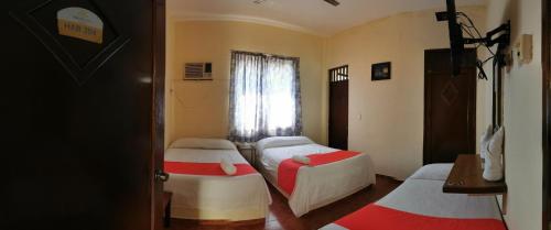a room with three beds and a window at Xpress Inn in Veracruz