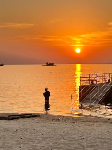 un homme debout dans l'eau à la plage au coucher du soleil dans l'établissement Flat 2 Suítes, piscina e churrasqueira em Alter, à Alter do Chão