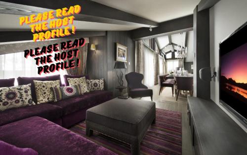 a living room with a purple couch and a tv at Luxury Chalet Courchevel with Pool & Jacuzzzi in Courchevel