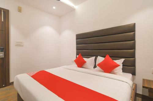 a bedroom with a large bed with red pillows at Hotel O Rudraksh in Indore