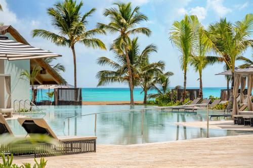 une piscine avec des palmiers et l'océan dans l'établissement Secrets Playa Esmeralda Resort & Spa - All Inclusive, à Miches