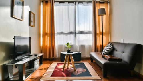 Una sala de estar con un sofá y un televisor. en Departamento completo con Vista a la Ciudad, a pasos del Metro Santa Isabel, Barrio Italia, providencia, en Santiago