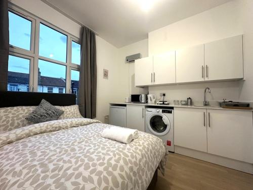 a bedroom with a bed and a washing machine at Finsbury Park Studio Apartments in London