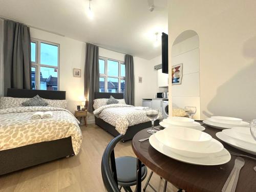 a bedroom with two beds and a table and chairs at Finsbury Park Studio Apartments in London