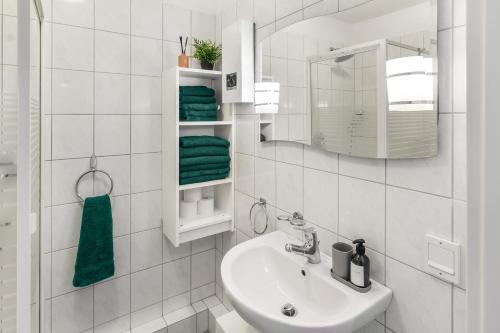 Un baño blanco con lavabo y espejo. en NEU Ruhige und gemütliche Wohnung mit Balkon, en Hagen