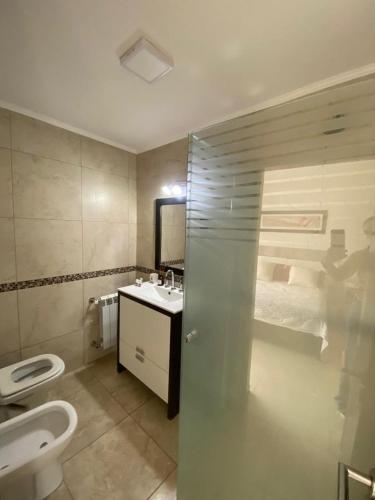 a bathroom with a toilet and a sink and a bed at Mendoza Aparts - Con cochera in Villa María