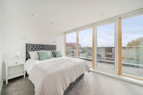 a white bedroom with a bed and a large window at Elegant One Bed Penthouse with Terrace in London