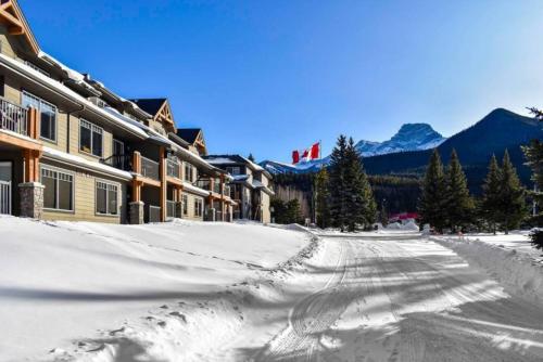 a snow covered street in front of a lodge at Cozy Condo With Hot Tub Gym and Underground Parking in Dead Man's Flats