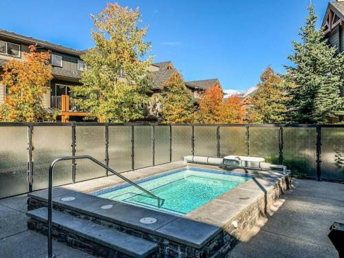 a hot tub in a backyard with a fence at Lovely 3BR condo with Hot Tub at the Edge of Canmore in Dead Man's Flats
