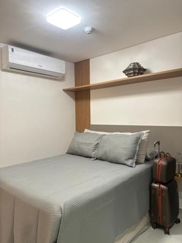 a small bedroom with a bed with a suitcase at Flat Moderno a 100m da Praia do Bessa in João Pessoa