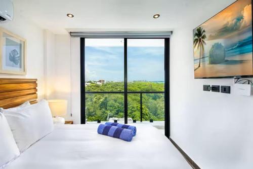a bedroom with a white bed with a large window at Cozy Playa Escape Pool, Beach & 5th Avenue in Playa del Carmen