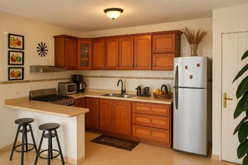 une cuisine avec des armoires en bois et un réfrigérateur blanc dans l'établissement Acogedor Apartamento en Punta Cana, a solo 8 minutos del Aeropuerto y las hermosas Playas, à Punta Cana