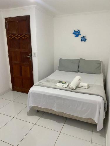 a bed in a white room with a door at Desfrutando de Arraial Apartamento in Arraial do Cabo