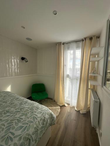 sypialnia z łóżkiem i zielonym krzesłem obok okna w obiekcie Le Duplex w mieście Argenteuil