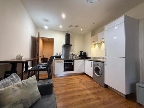 a kitchen with white appliances and a table and a couch at Modern 2BR Flat in Bradford City Centre! in Bradford
