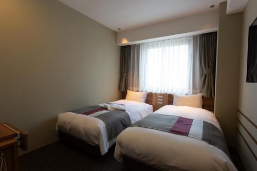 a hotel room with two beds and a window at Shinsaibashi Grand Hotel Osaka in Osaka