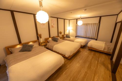 a hotel room with three beds and two pendant lights at oyadoya gifu kano 岐阜駅徒歩12分 名古屋駅35分 大人数貸切 最大8名 駐車場有り in Gifu