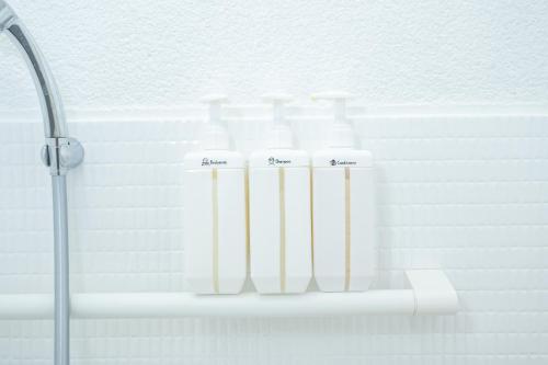 a row of white bottles on a shelf in a bathroom at oyadoya gifu kano 岐阜駅徒歩12分 名古屋駅35分 大人数貸切 最大8名 駐車場有り in Gifu