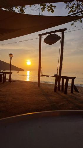 a picnic table on the beach with the sunset at Espaço Villa Ará in Praia de Araçatiba