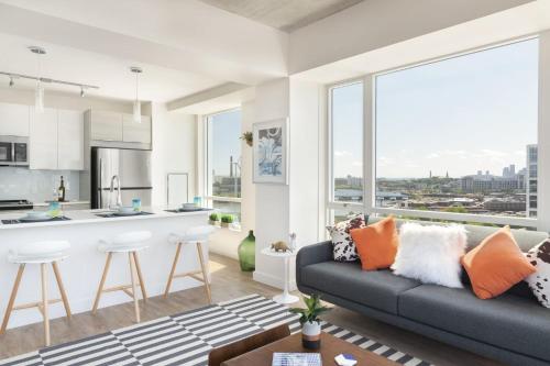 a living room with a couch and a kitchen with large windows at Luxury Apartments by Hyatus at Boston Assembly Row in Somerville