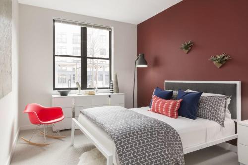 a bedroom with a white bed and a red wall at Luxury Apartments by Hyatus at Boston Assembly Row in Somerville