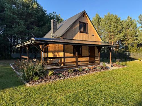 a wooden house with a gambrel roof on a field at Dolina Jelenia in Gorczyca