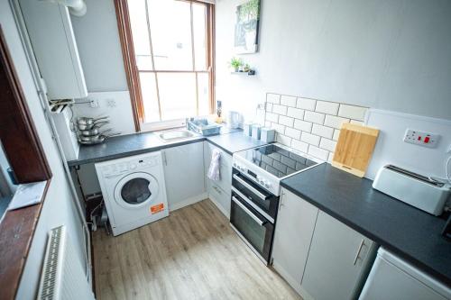 a kitchen with a sink and a washing machine at 1 BDR Apartment By Eason Stays Short Lets & Serviced Accommodation Lowestoft With Free parking in Lowestoft