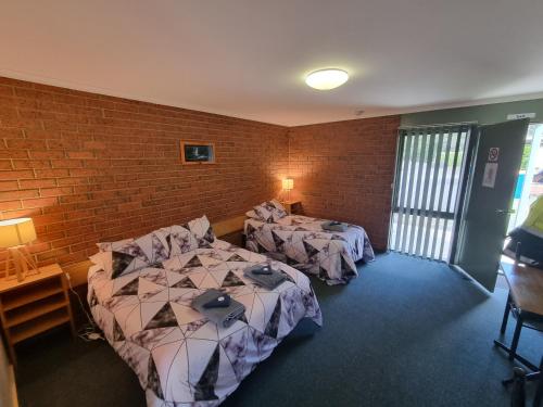 a room with two beds and a brick wall at 1st T Motel in Mirboo North
