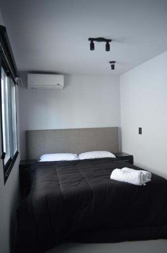 ein Schlafzimmer mit einem schwarzen Bett mit zwei weißen Kissen in der Unterkunft BoxPoint MotoResort in Cordoba