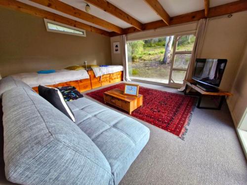 a bedroom with a couch and a tv and a bed at The Stone Cottage - Bruny Island in Simpsons Bay