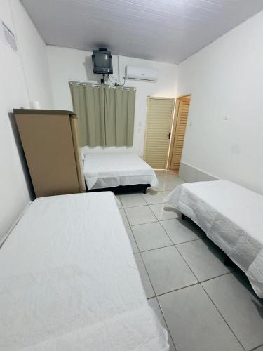 a bedroom with two beds and a tv on the wall at Hotel Pousada Aquarius SOB NOVA DIREÇÃO in Aruanã