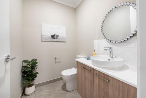 Un baño con lavabo, inodoro y espejo. en The Peninsula Pearl - Luxe by the Bay with Heated Pool, en Safety Beach