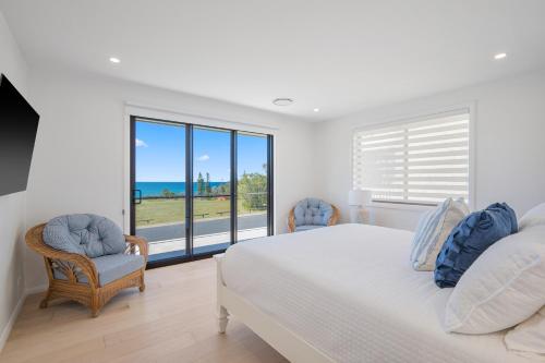 1 dormitorio blanco con 1 cama y 2 sillas en 13 Jordan, en Bonny Hills