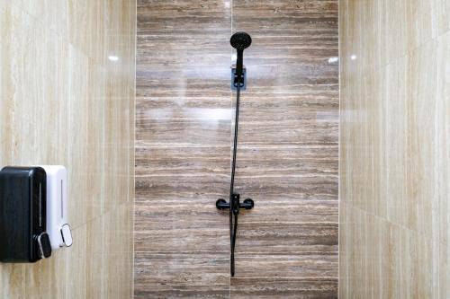 eine Glasduschtür mit einem schwarzen Griff an einer Holzwand in der Unterkunft RedDoorz @ myRoom UMY in Yogyakarta