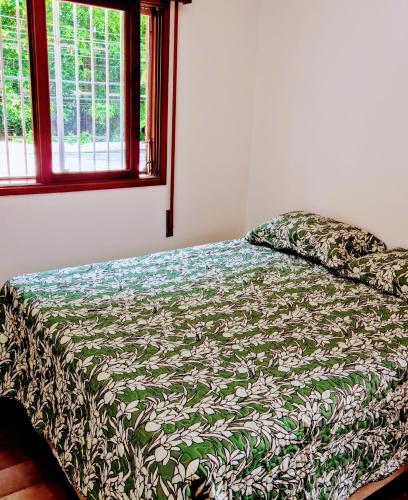 a bed with a green and white comforter and a window at Quarto próximo Consulado Americano e metrô Borba Gato in São Paulo