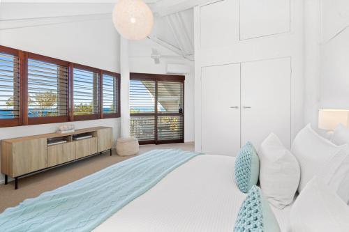 een witte slaapkamer met een groot bed en ramen bij The Whitewater House, Peregian Beach in Peregian Beach