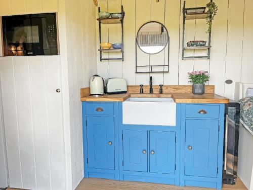 a blue kitchen with a sink and a mirror at The Carriage - Uk48947 in Shirland