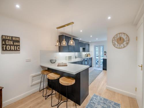 a kitchen with blue cabinets and a counter with stools at Warrington House-Uk48465 in Thornton Dale