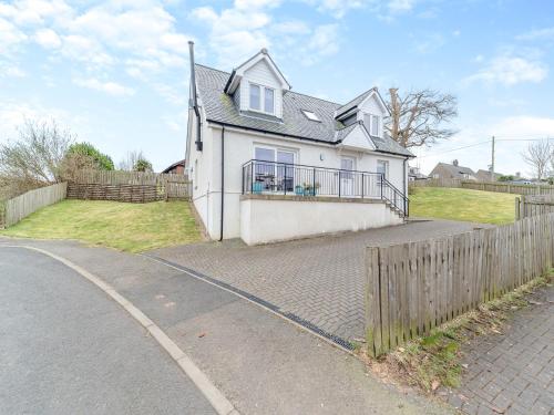 a white house with a fence on the side of a road at Springbank in Brodick