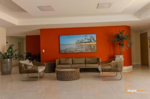 グアラジュバにあるFlat Vista Lago Perto do Mar em Guarajubaのソファと椅子、オレンジ色の壁のあるロビー