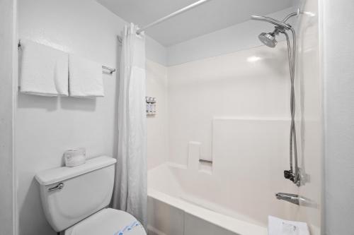 Un baño blanco con inodoro y ducha. en Hotel Milagro, en Chula Vista